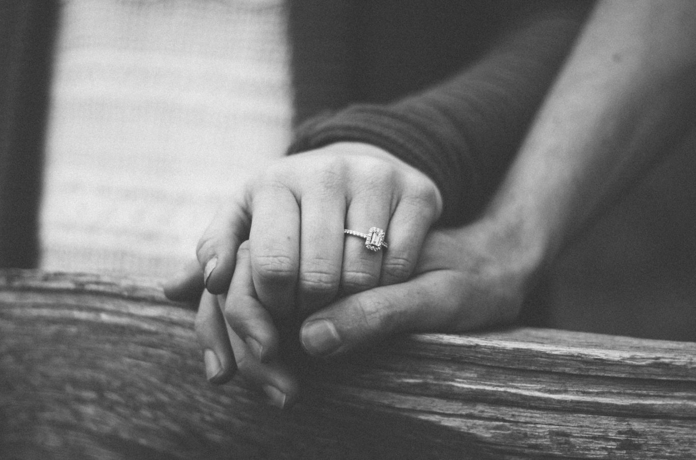 Zwei Hände halten sich, eine trägt einen Ring. Intimate Geste von Zuneigung.