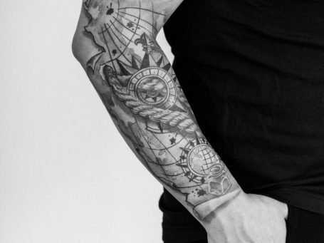 Schwarze und graue Tattoos auf dem Unterarm eines Mannes, detailliertes Design.