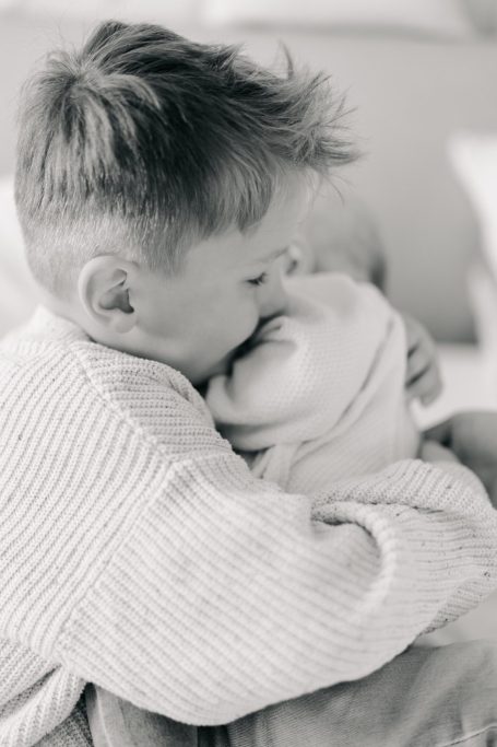 Ein Erwachsener hält die kleinen Hände eines Babys in einer sanften Berührung.