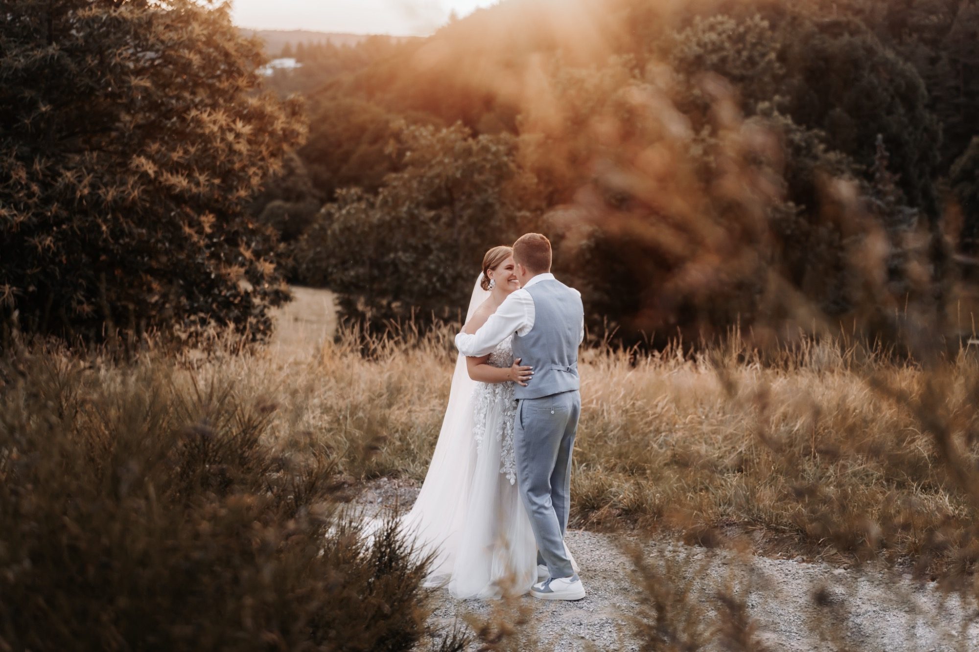 Händchenhaltende Brautpaar mit Blumenstrauß und Brautring.